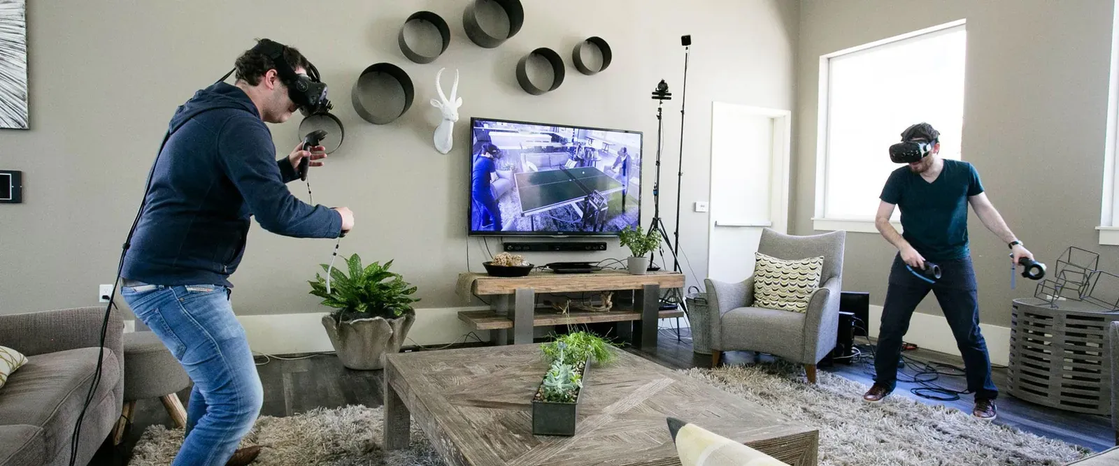 Two people using VR headsets in a living room