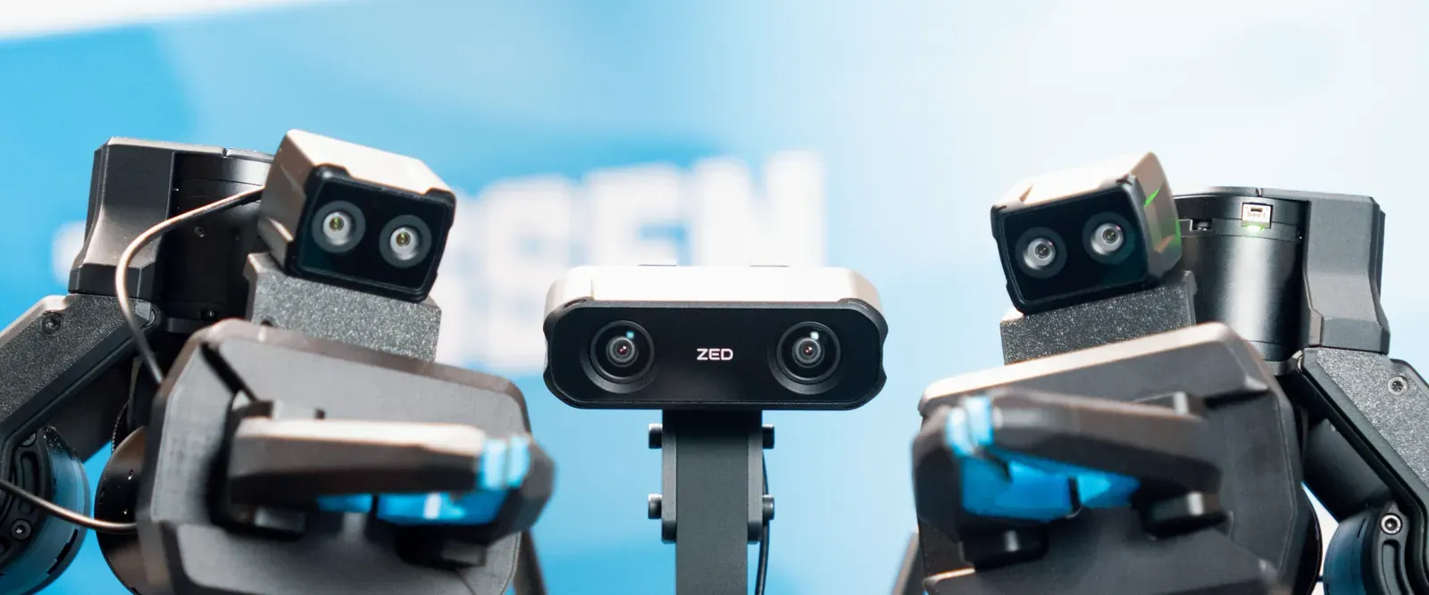 Two robot grippers with a ZED X Nano on each wrist and a ZED X Mini between them